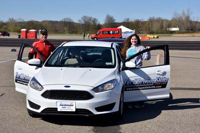 Juan Babun, Ford Driving Skills for Life coach, stands with the passenger side door as a student stands near the driver's side door in preparation to drive a speed and pace management course